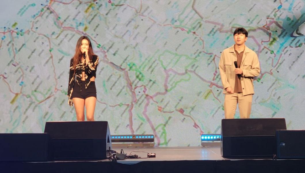 Two people standing on a stage while holding microphones and singing a song.